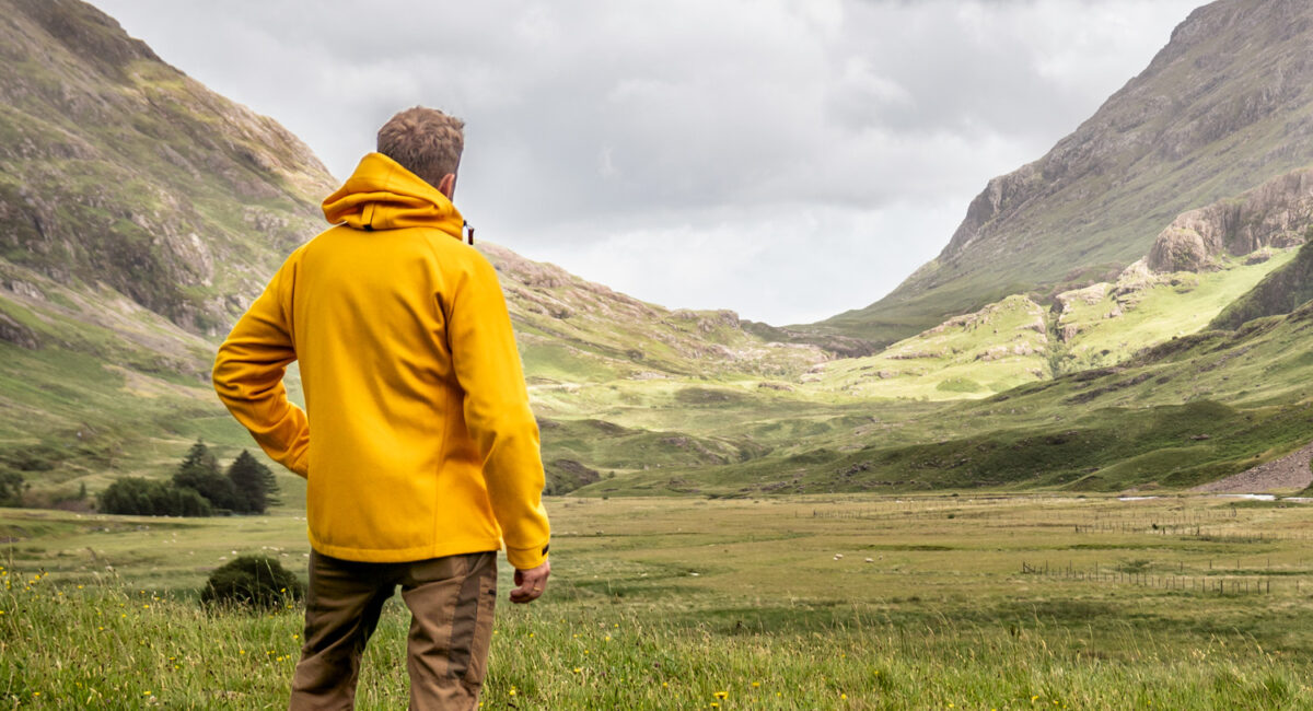Mann mit gelber Kapuzenjacke in schottischen Highlands