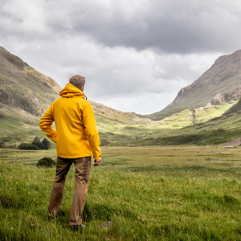 Mann mit gelber Kapuzenjacke in schottischen Highlands